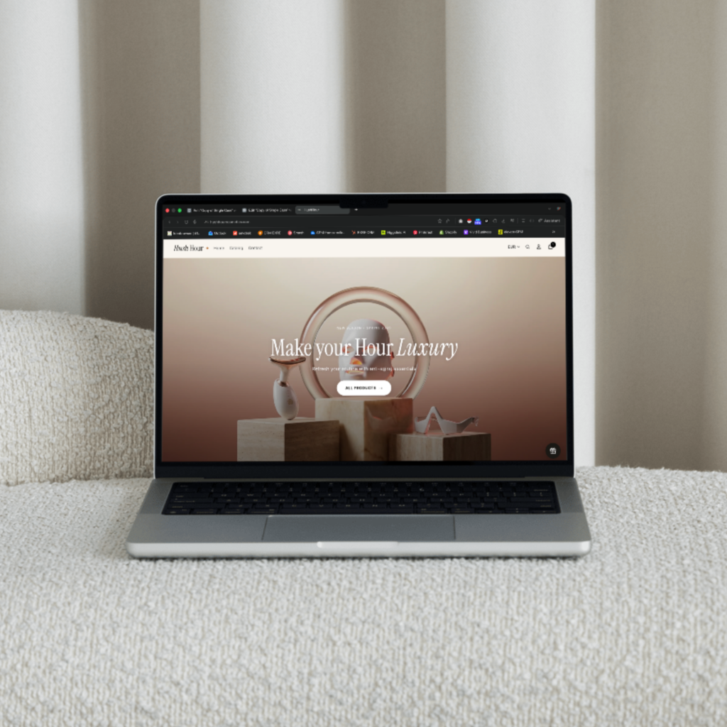 Laptop on a textured sofa showing the HushHour Cosmetics Shopify homepage with LED beauty devices hero banner and Make your Hour Luxury headline, highlighting the responsive beauty-tech store design.